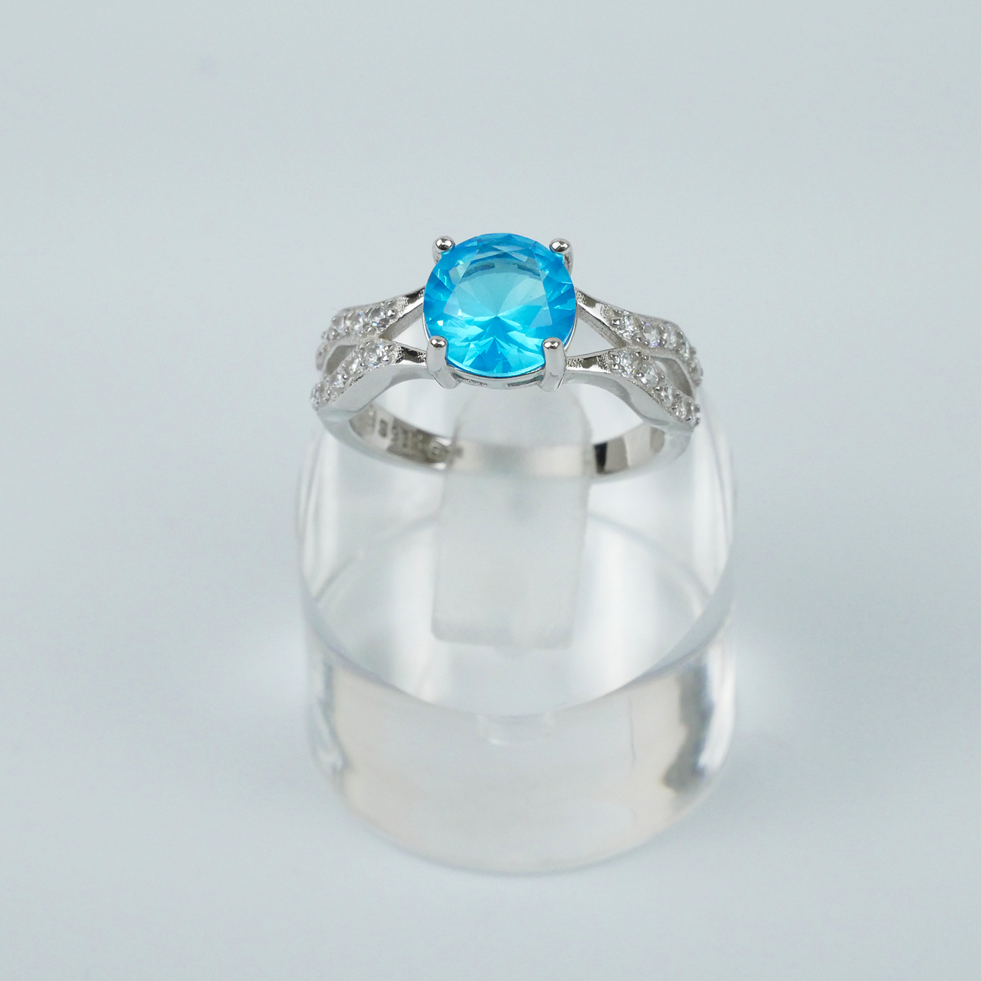 Silver ring with a blue gemstone on a light gray background