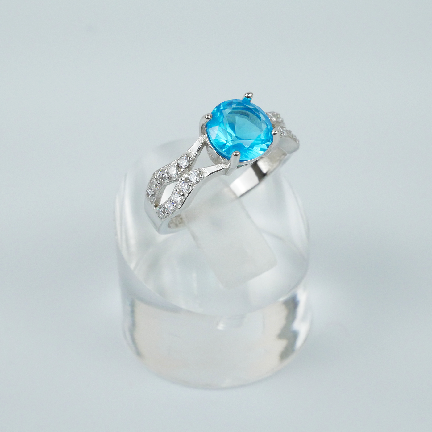 Silver ring with a blue gemstone on a light gray background