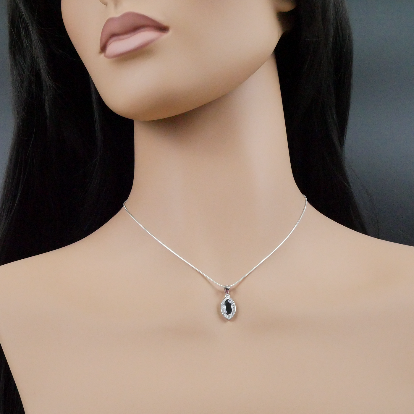 Mannequin wearing a silver necklace with a pendant on a dark background