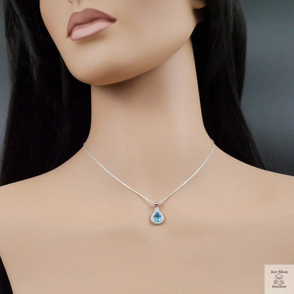 Mannequin wearing a silver necklace with a teardrop-shaped pendant on a dark background
