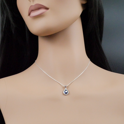 Mannequin wearing a silver necklace with a teardrop pendant on a dark background