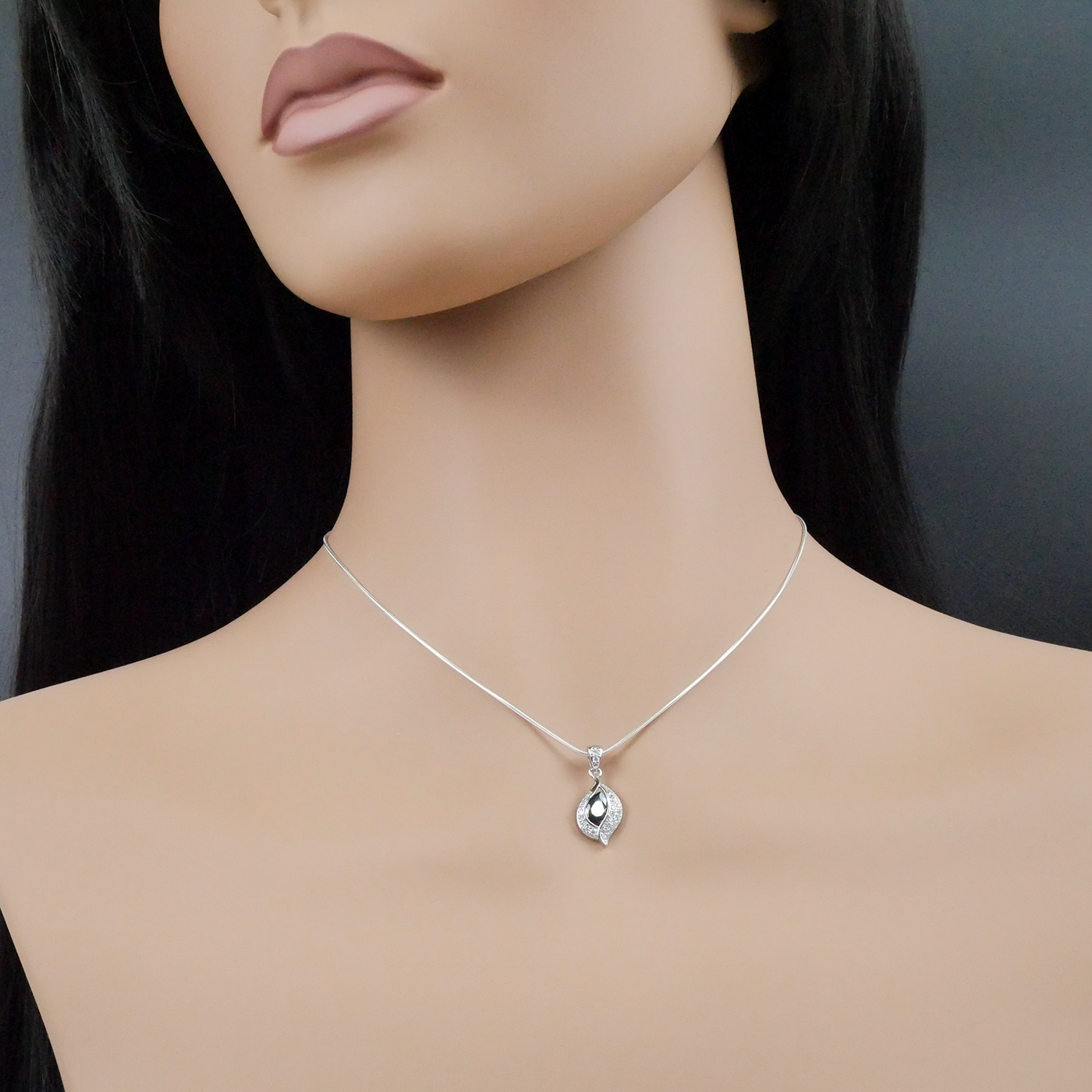 Mannequin wearing a silver necklace with a pendant on a dark background