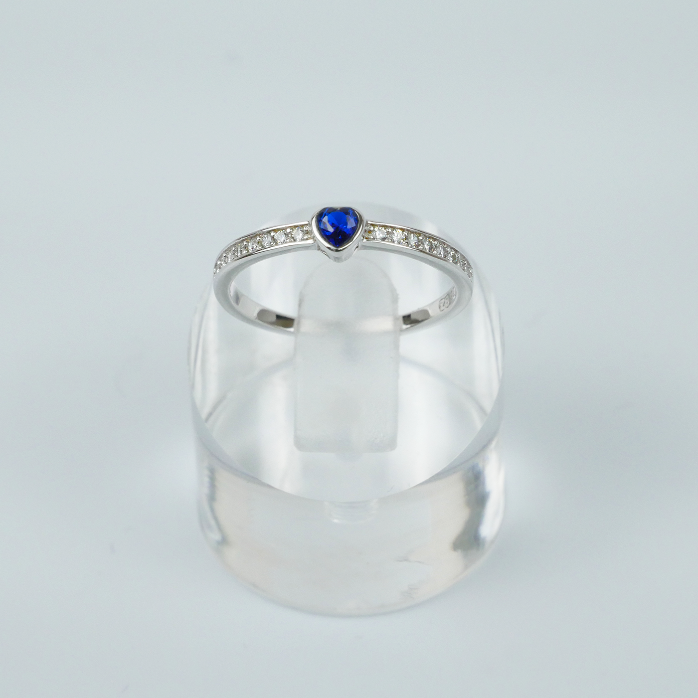 Silver ring with a blue gemstone on a light gray background