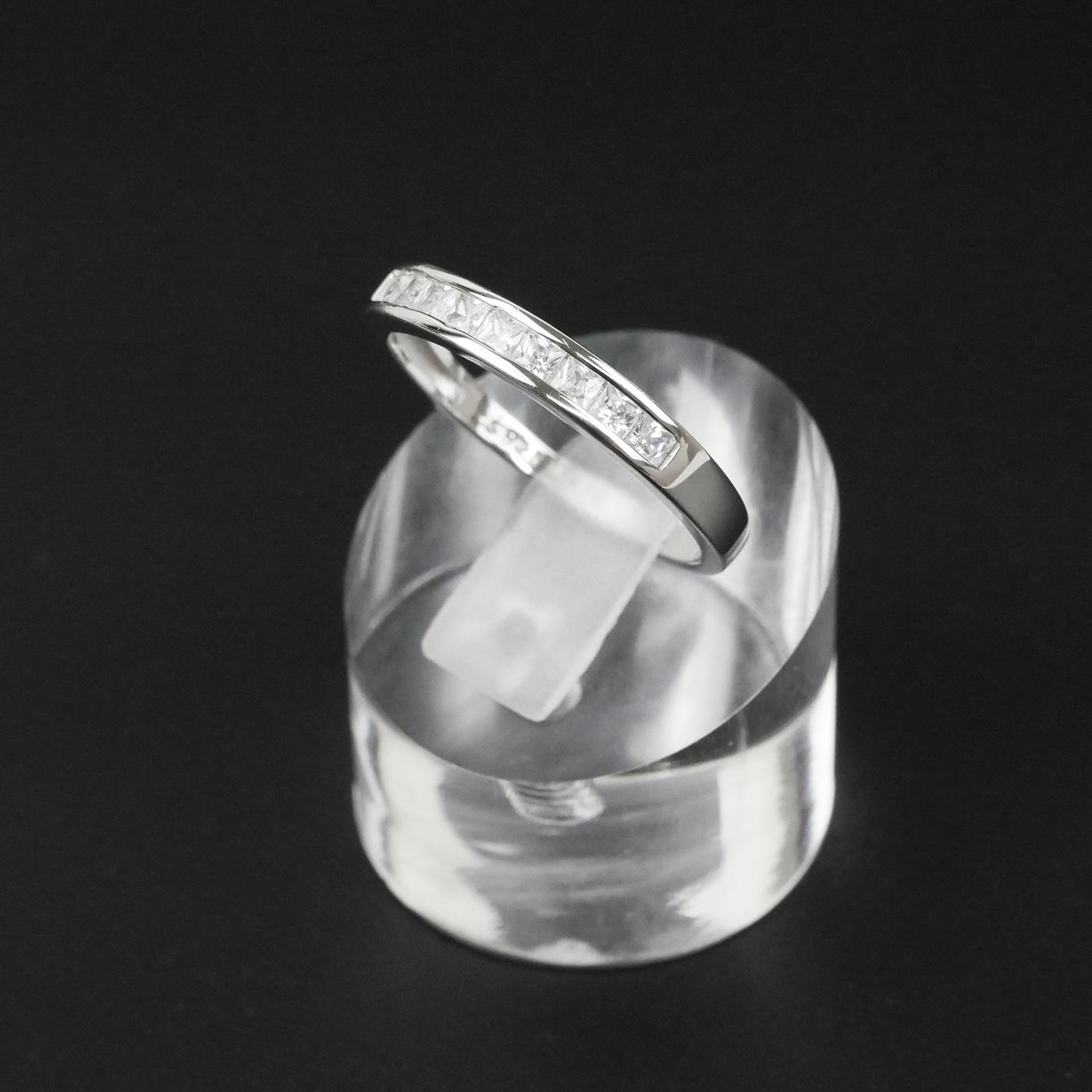 Silver ring on a clear stand against a black background