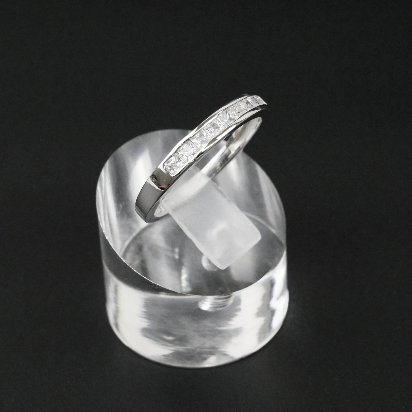 Silver ring on a clear stand against a black background