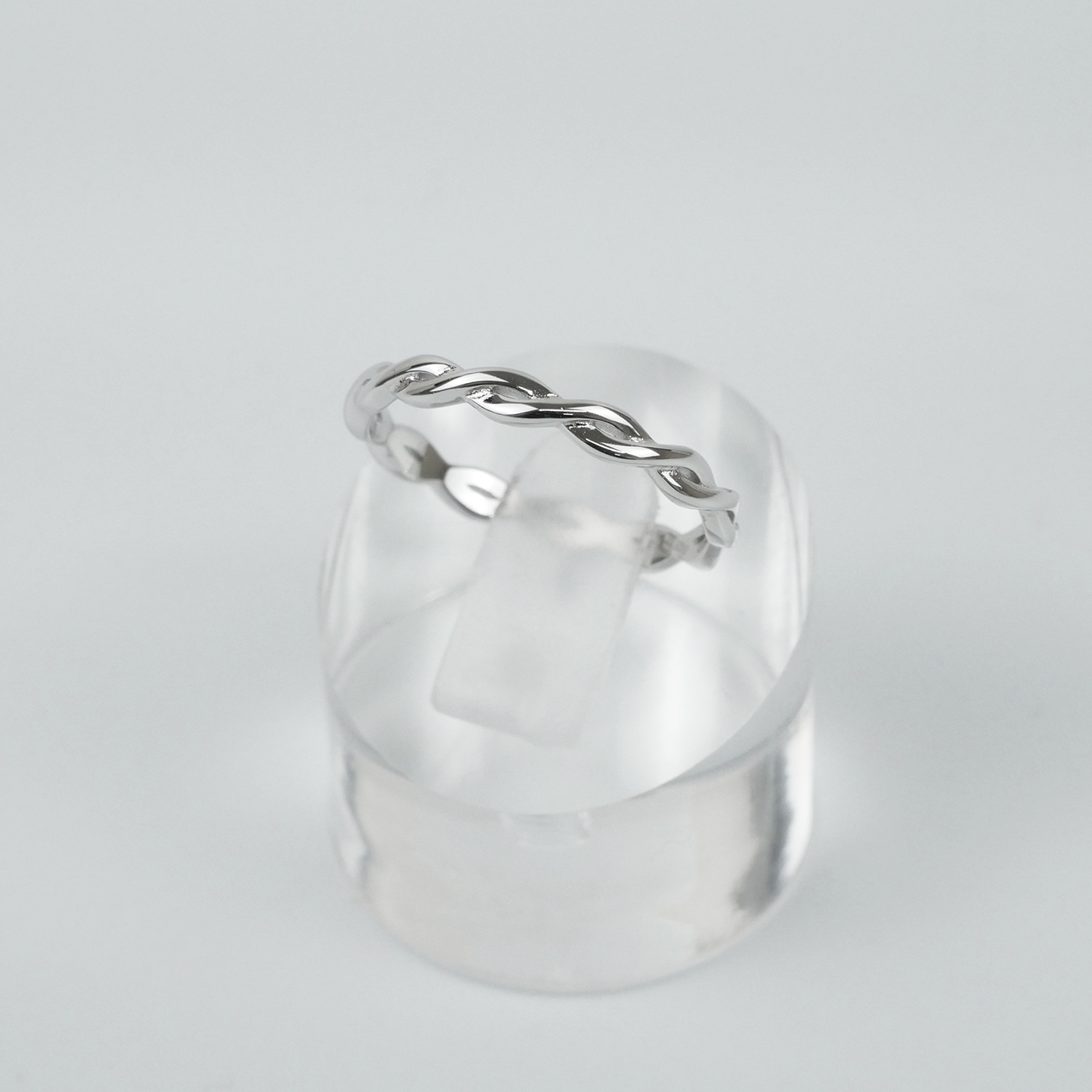 Silver ring with a twisted design on a light gray background