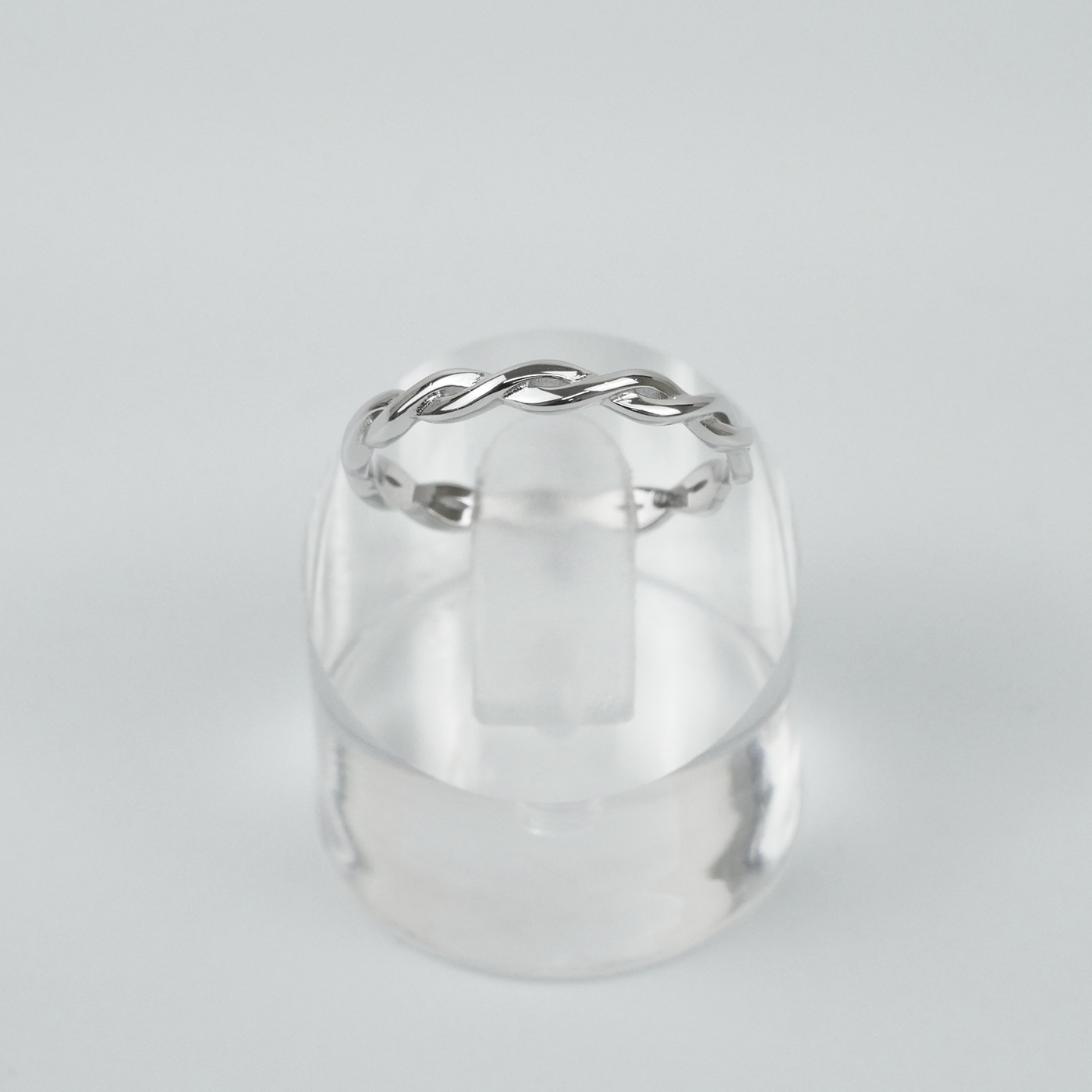 Silver ring with a twisted design on a light gray background