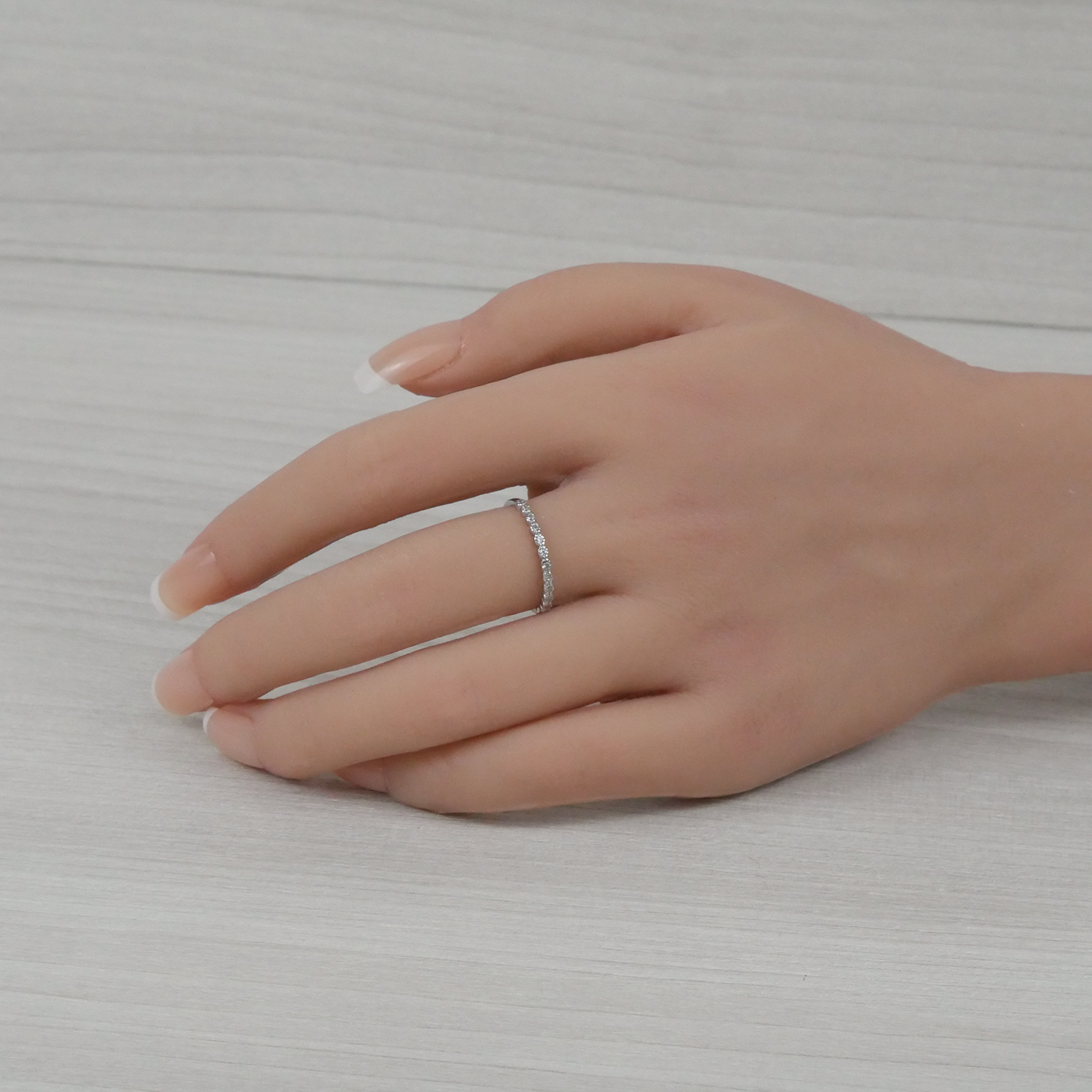Hand wearing a silver ring on a light gray background