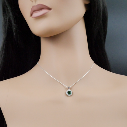Mannequin wearing a silver necklace with a green gemstone pendant on a dark background