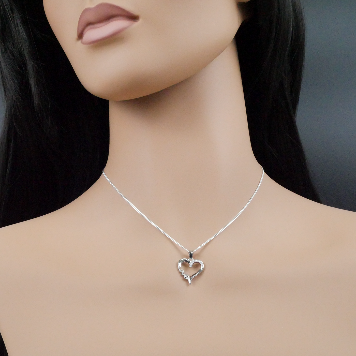 Silver heart-shaped necklace on a mannequin with a dark background