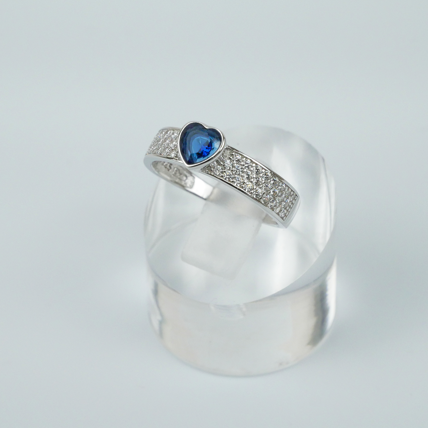 Silver ring with a blue gemstone on a light gray background