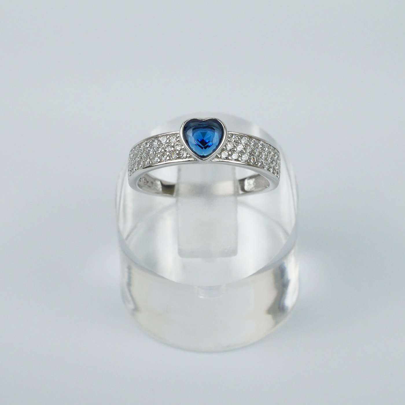 Silver ring with a blue gemstone on a light gray background