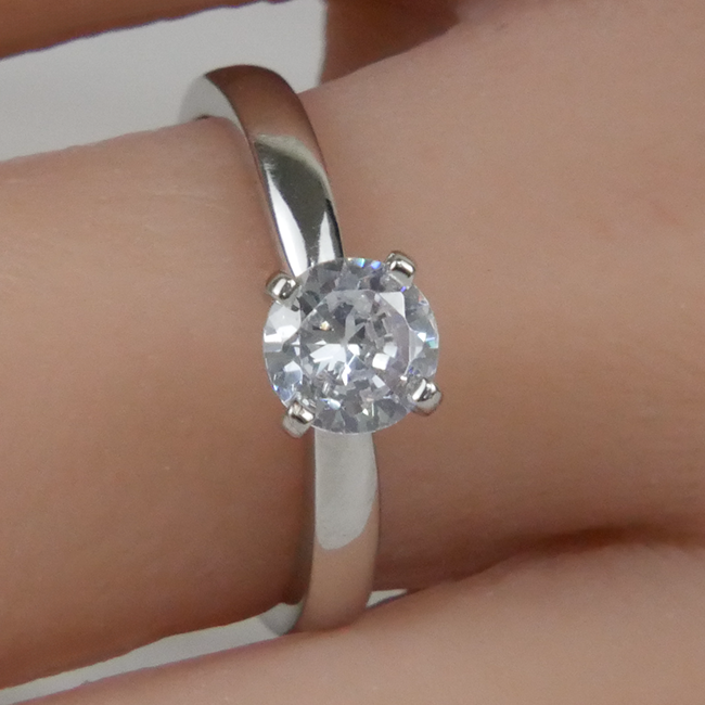 Silver ring with a Zirconia on a finger against a neutral background