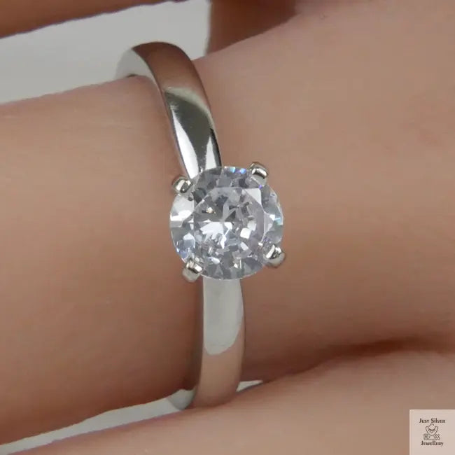 Silver ring with a Zirconia on a finger against a neutral background