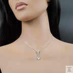 Mannequin wearing a silver necklace with a teardrop pendant on a dark background
