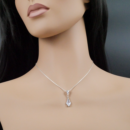 Mannequin wearing a silver necklace with a teardrop pendant on a dark background