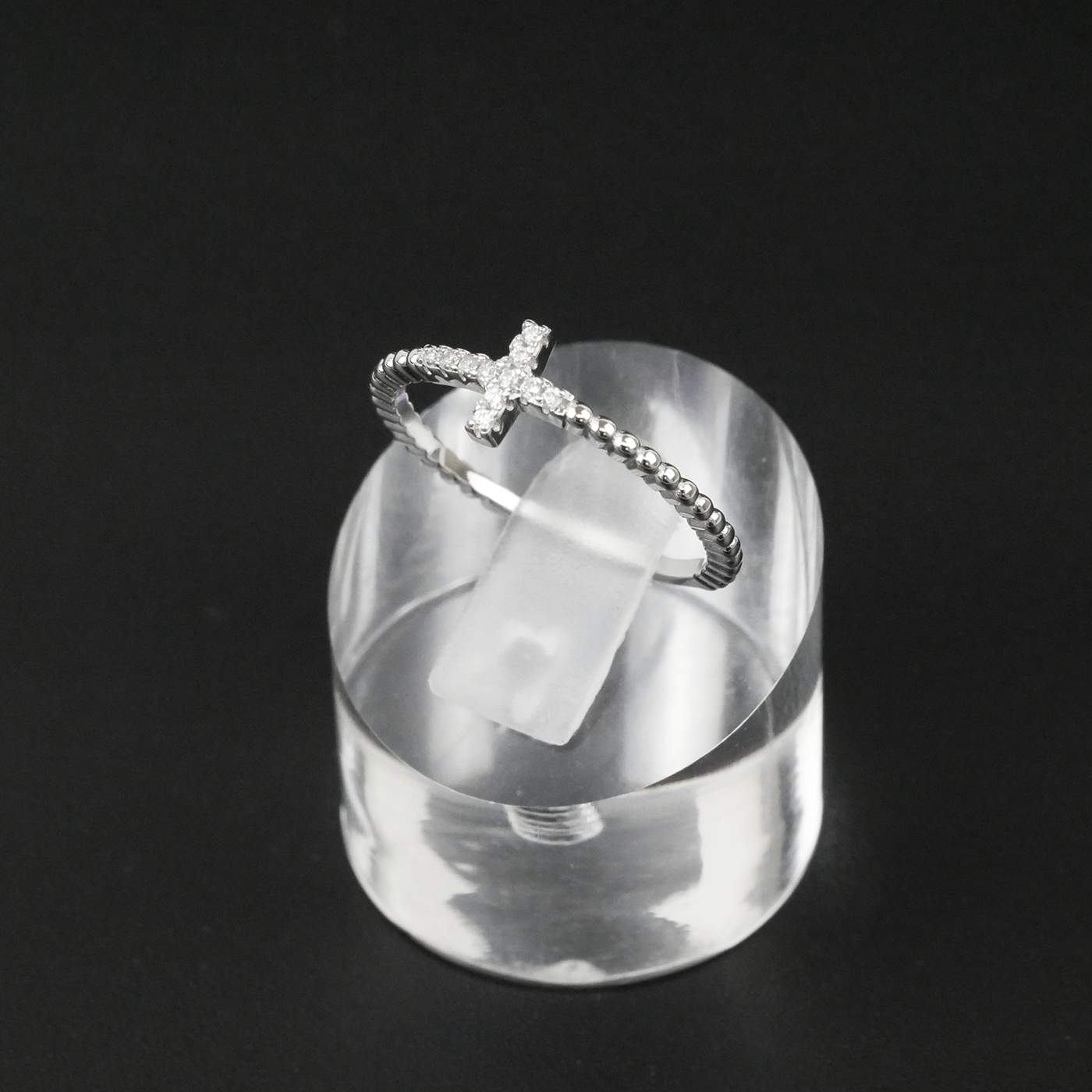 Silver ring with a unique design on a clear stand against a black background