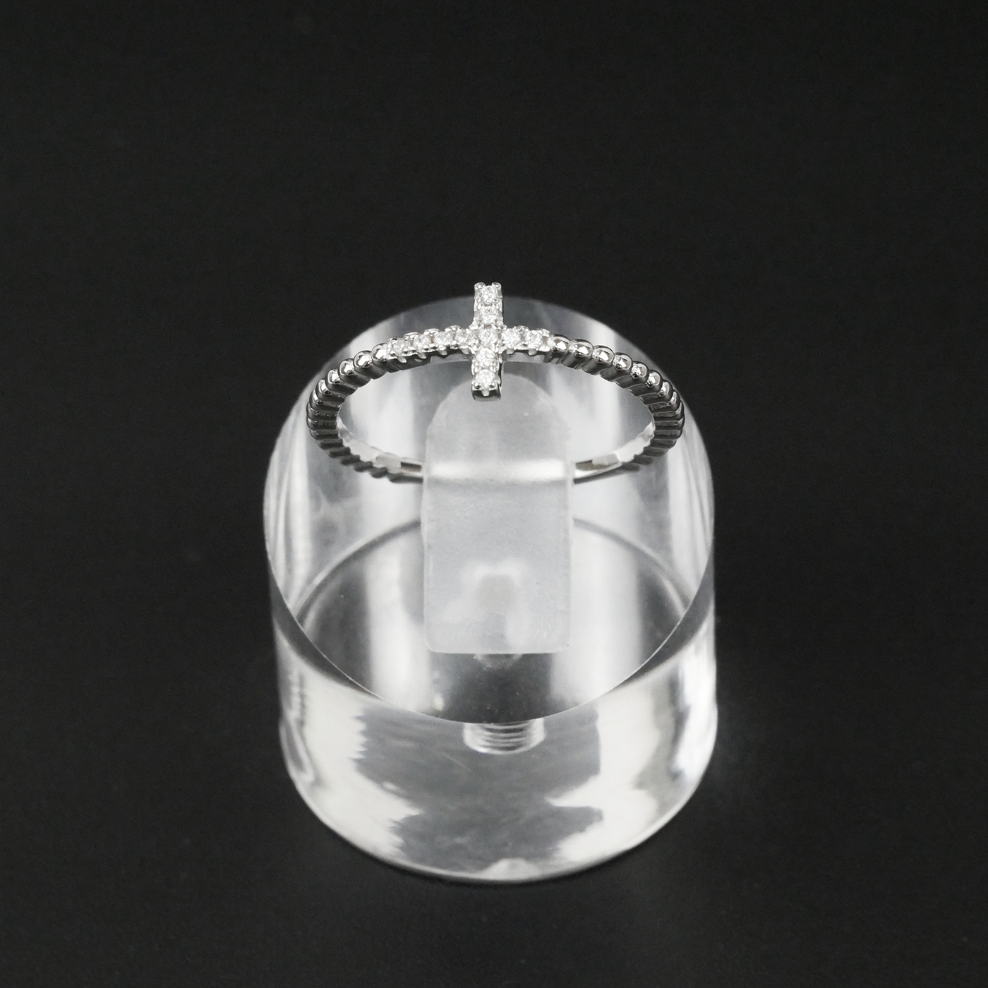 Silver ring with a unique design on a clear stand against a black background