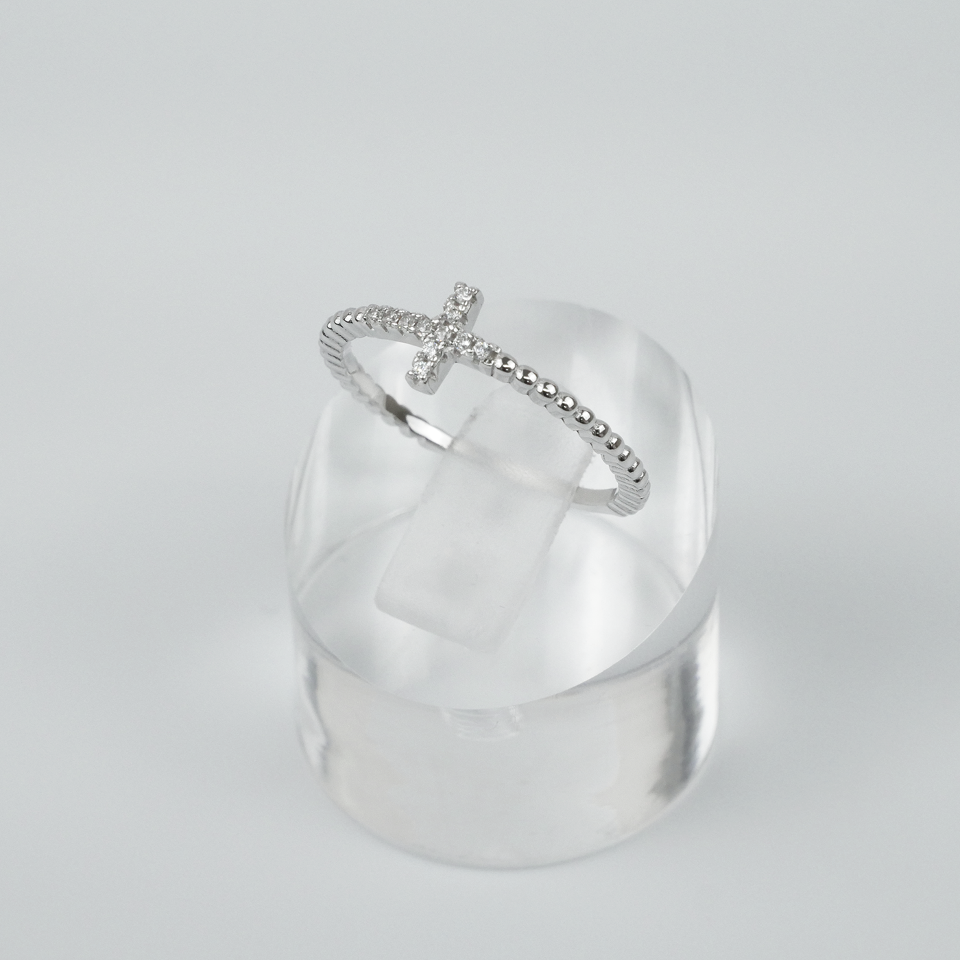 Silver ring with a unique design on a clear stand against a light grey background
