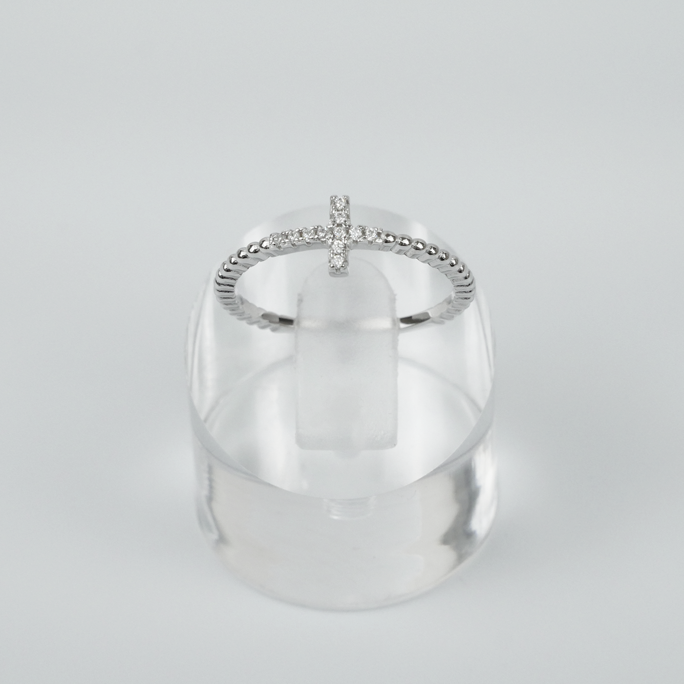 Silver ring with a unique design on a clear stand against a light grey background