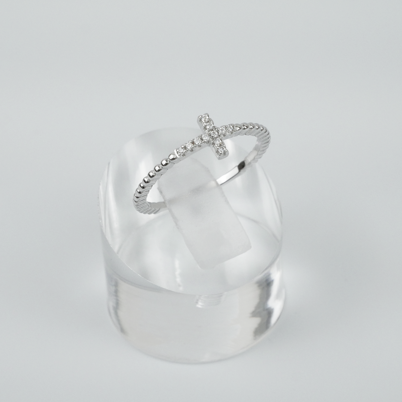 Silver ring with a unique design on a clear stand against a light grey background