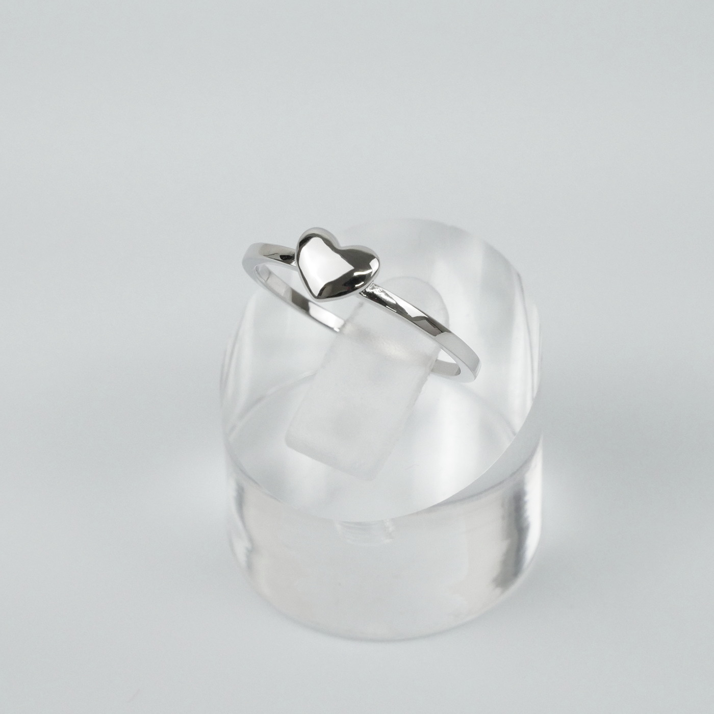 Silver ring with a heart-shaped design on a light grey background