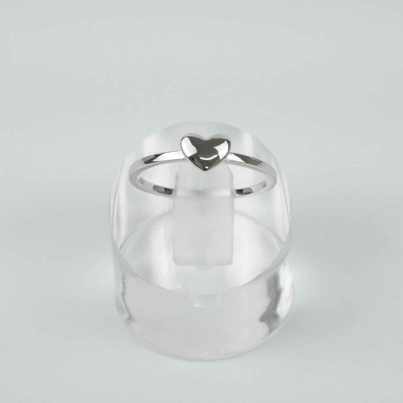 Silver ring with a heart-shaped design on a light grey background