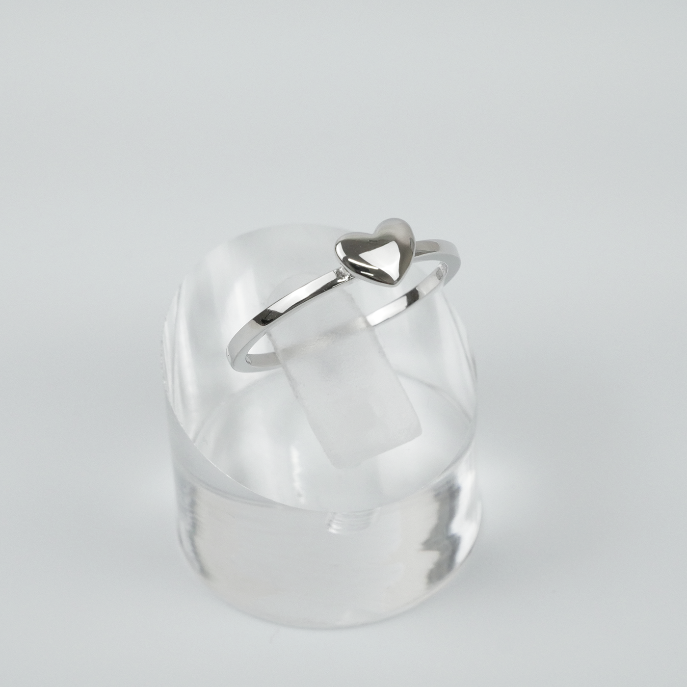 Silver ring with a heart-shaped design on a light grey background