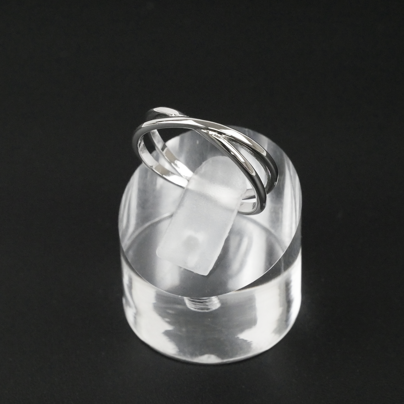 Silver ring on a clear stand against a black background