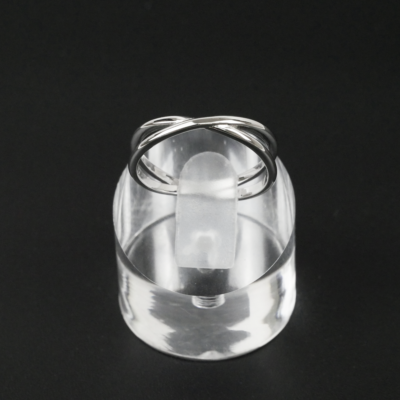 Silver ring on a clear stand against a black background