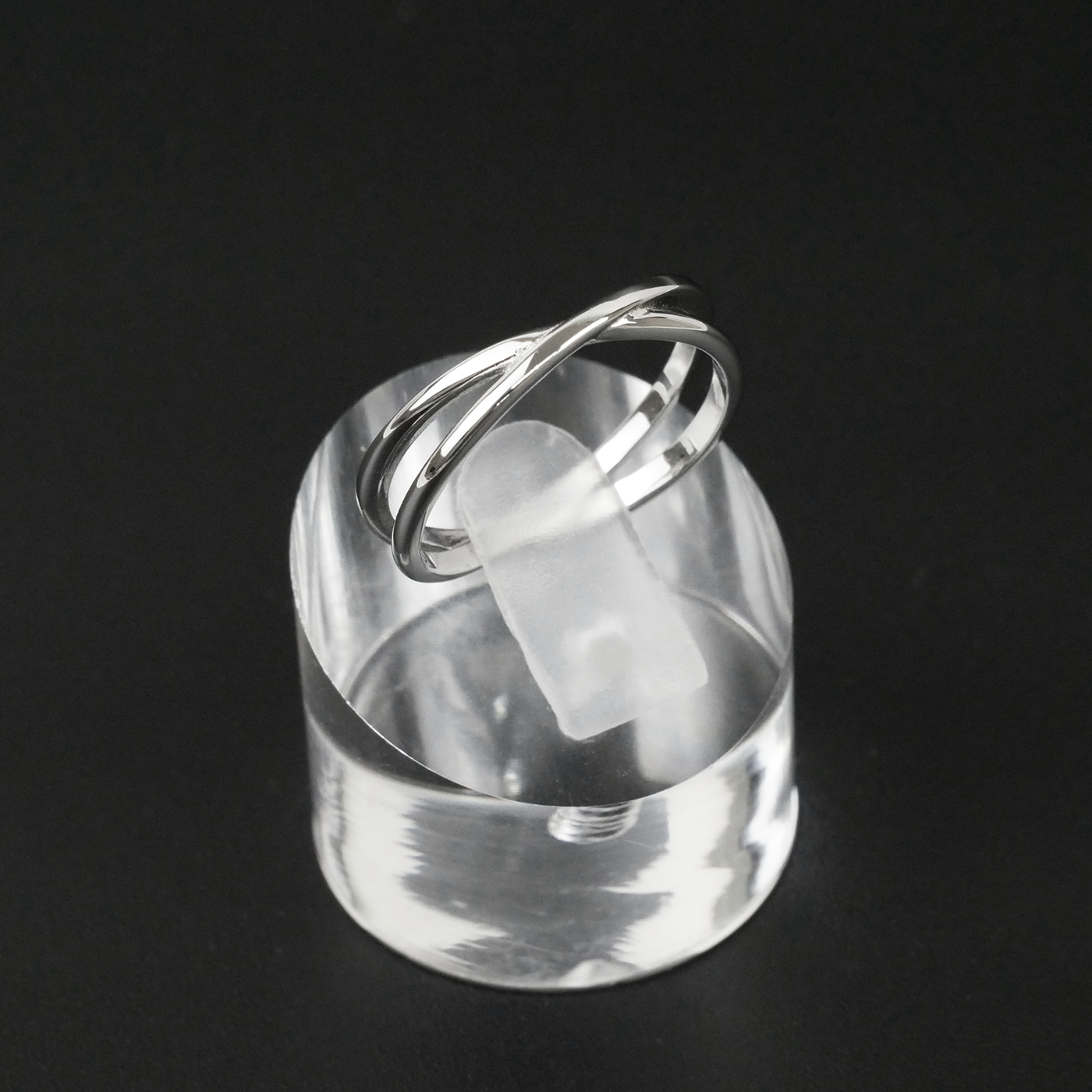 Silver ring on a clear stand against a black background