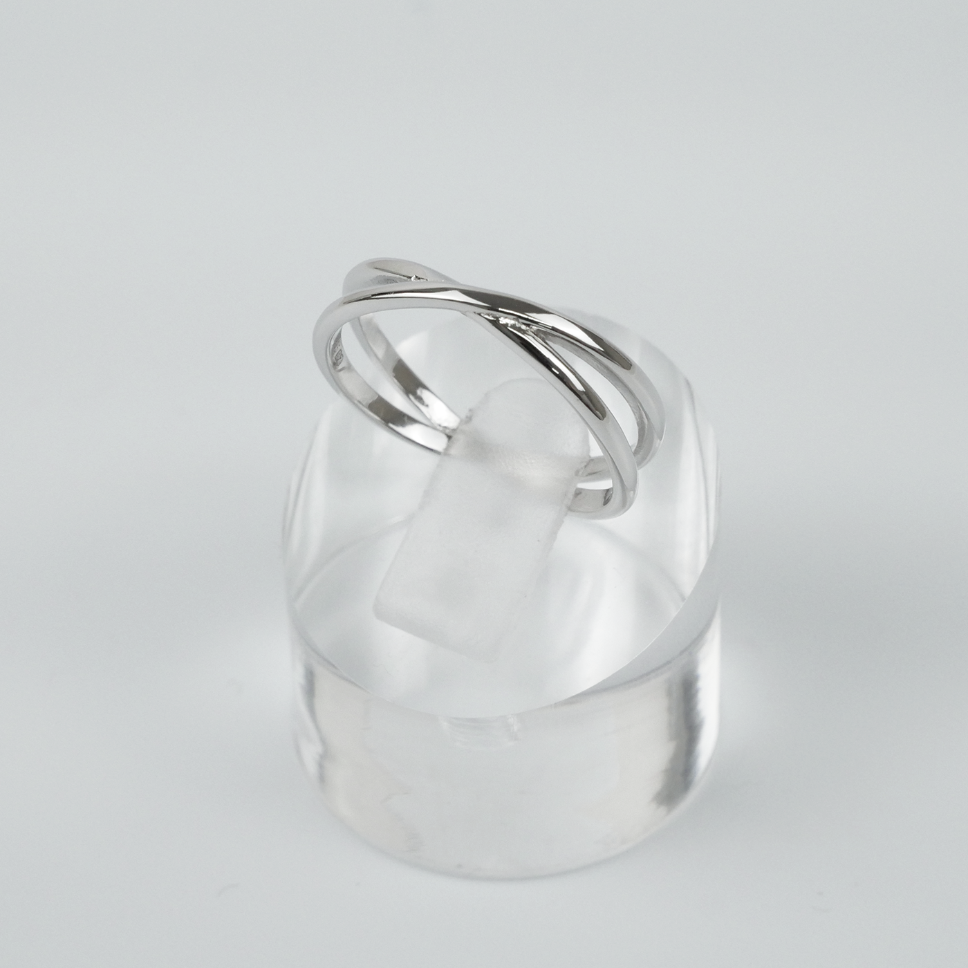 Silver ring on a clear stand against a light gray background