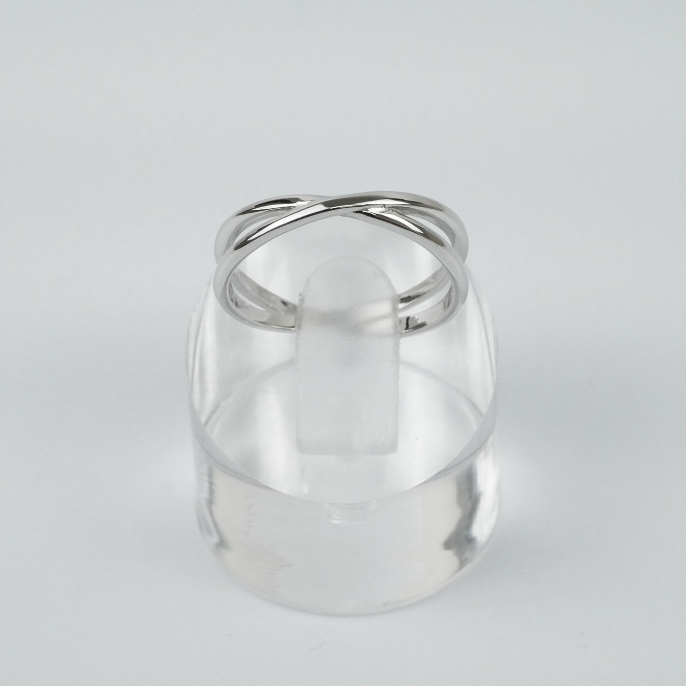 Silver ring on a clear stand against a light gray background