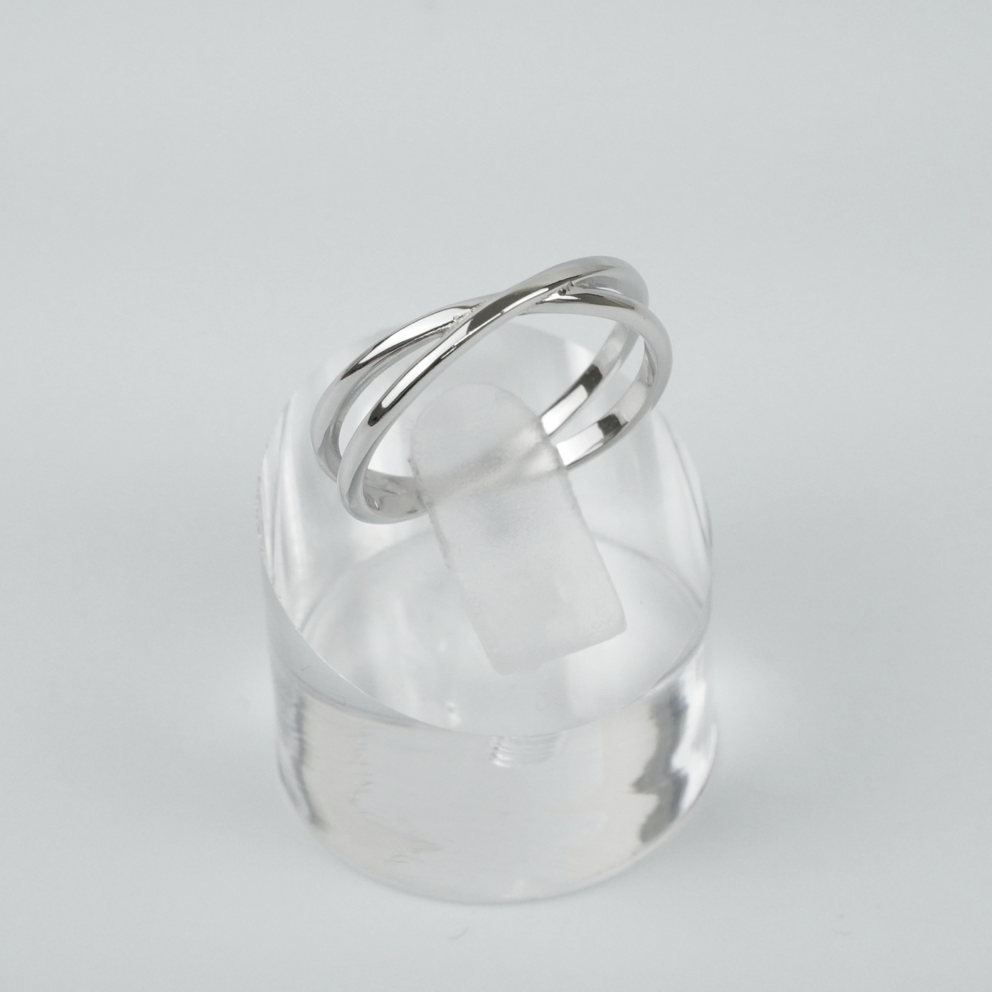 Silver ring on a clear stand against a light gray background