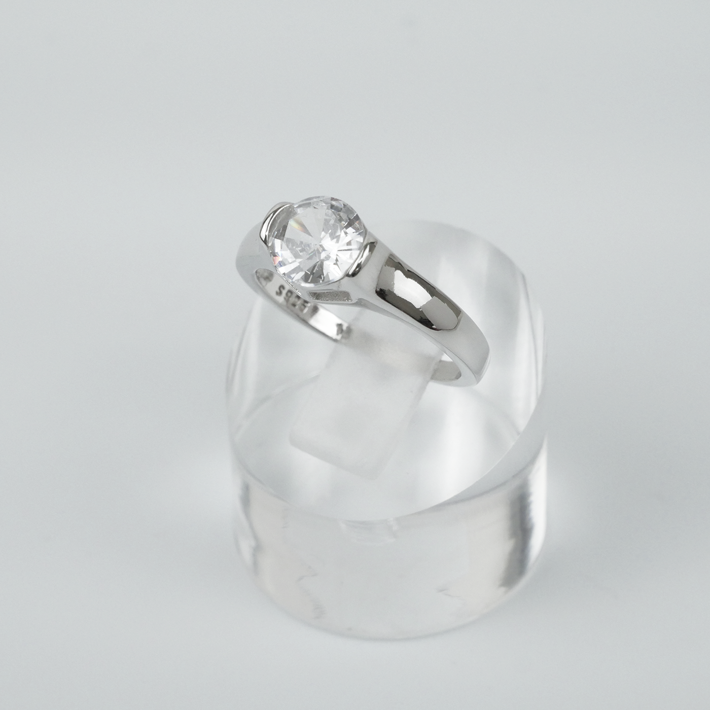 Silver ring with a clear gemstone on a light gray background
