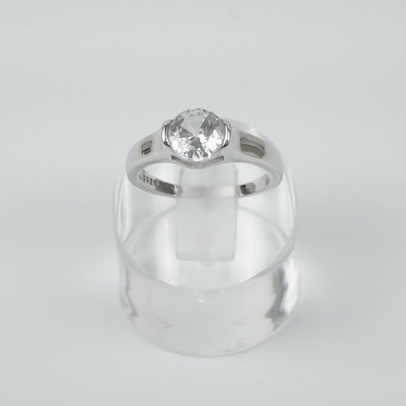 Silver ring with a clear gemstone on a light gray background