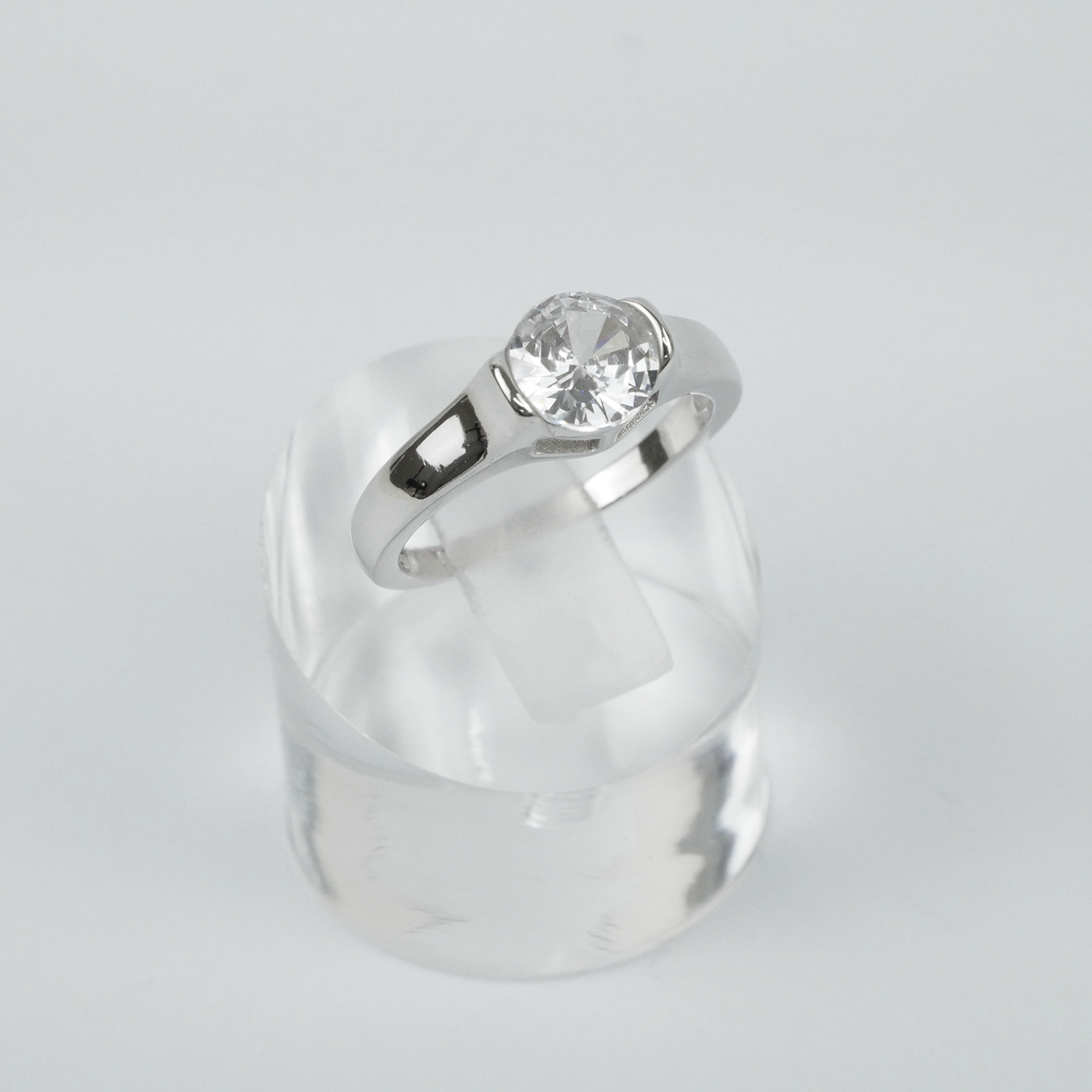 Silver ring with a clear gemstone on a light gray background
