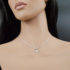 Mannequin wearing a silver necklace with a mouse-shaped pendant on a dark background