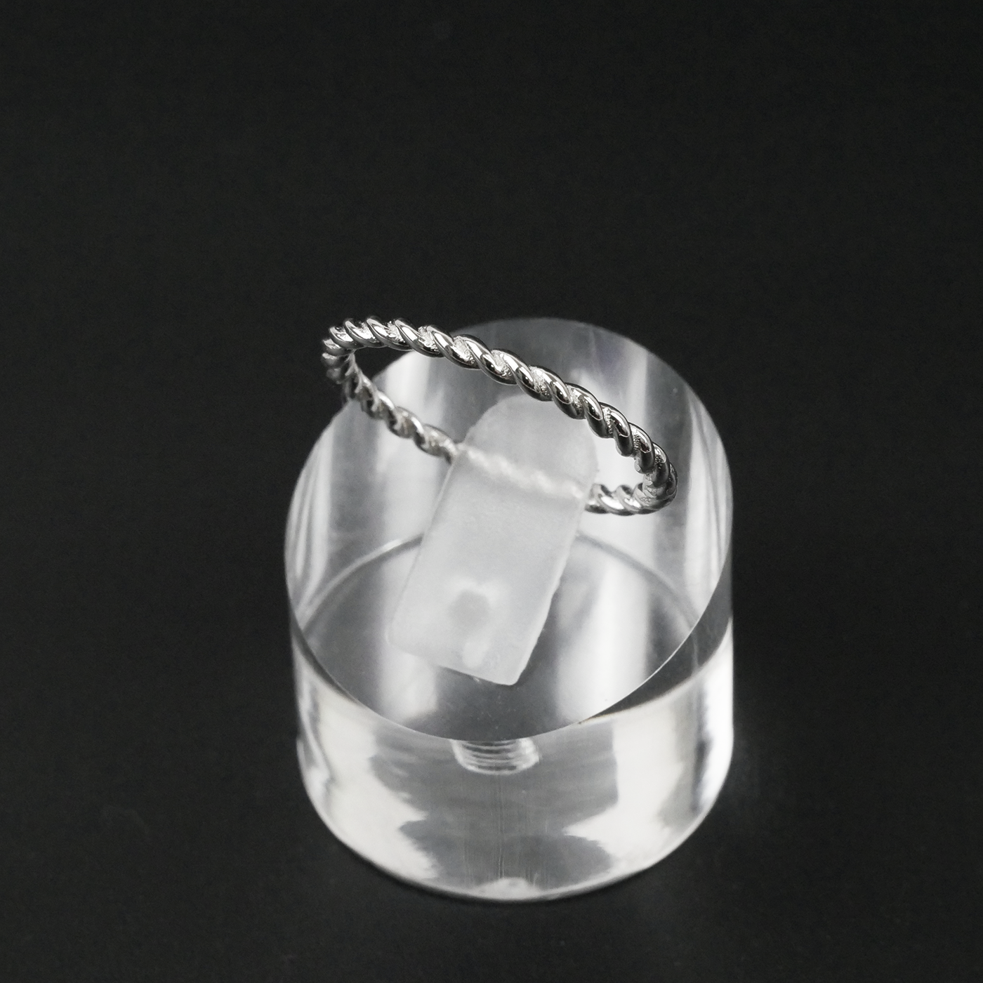 Silver ring with a twisted design on a black background