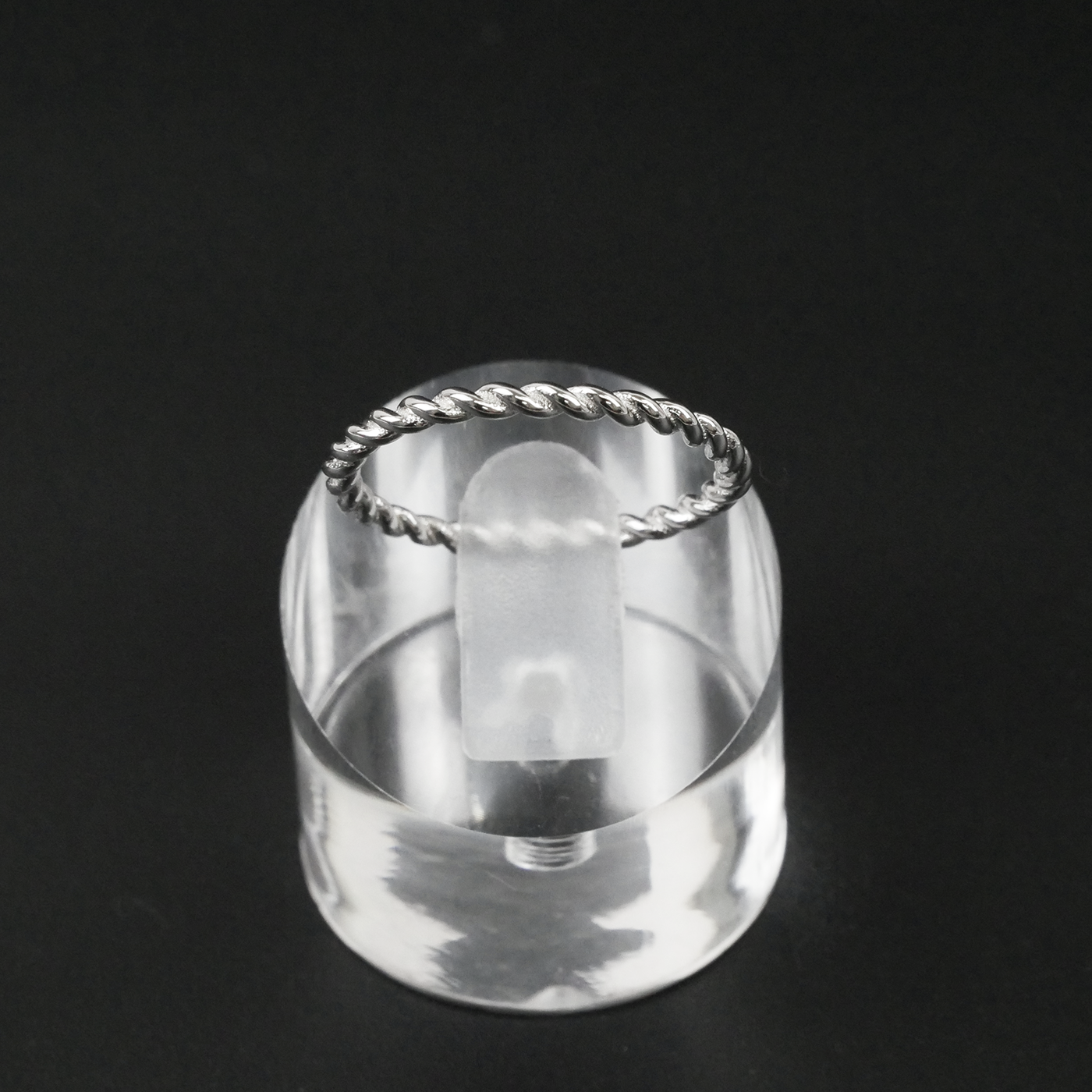 Silver ring with a twisted design on a black background