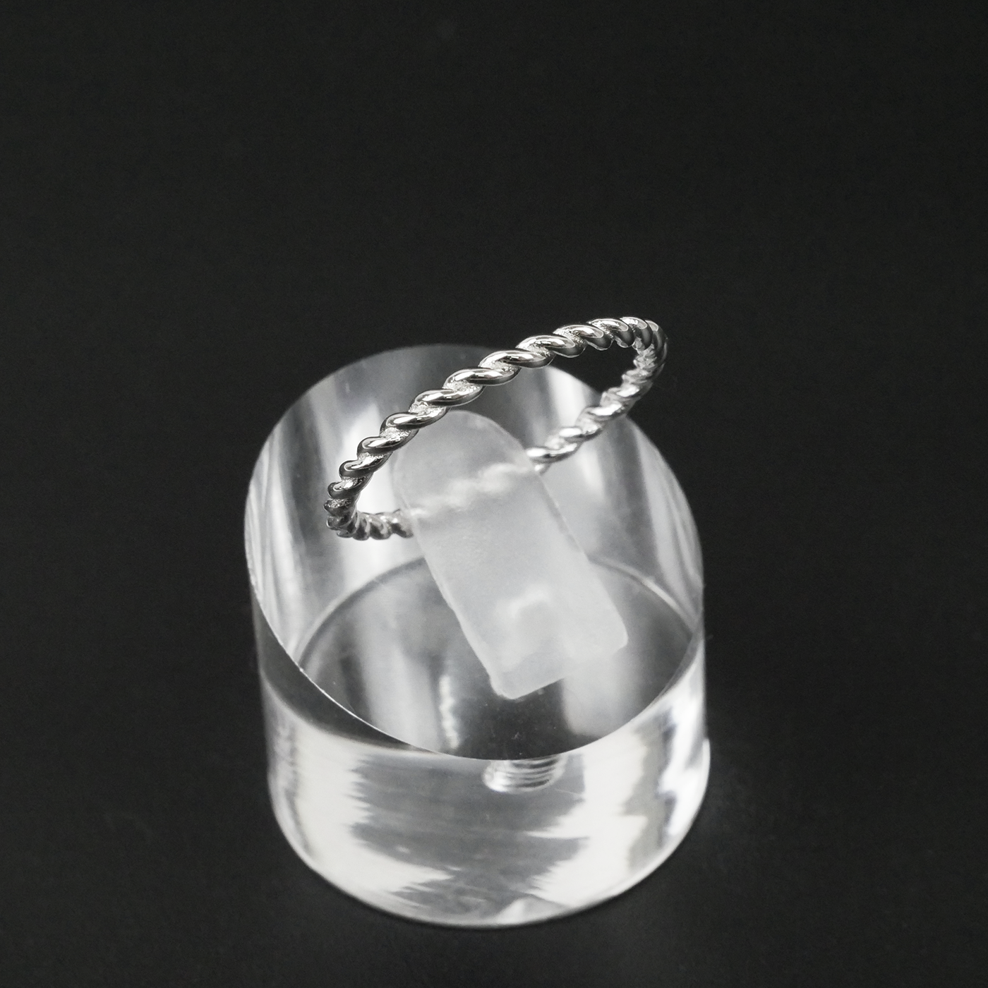 Silver ring with a twisted design on a black background