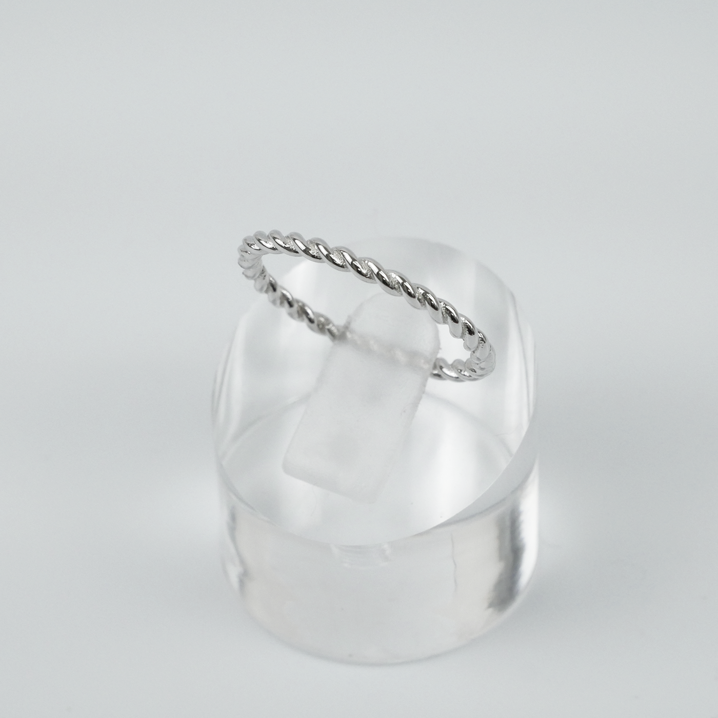 Silver ring with a twist design on a light grey background