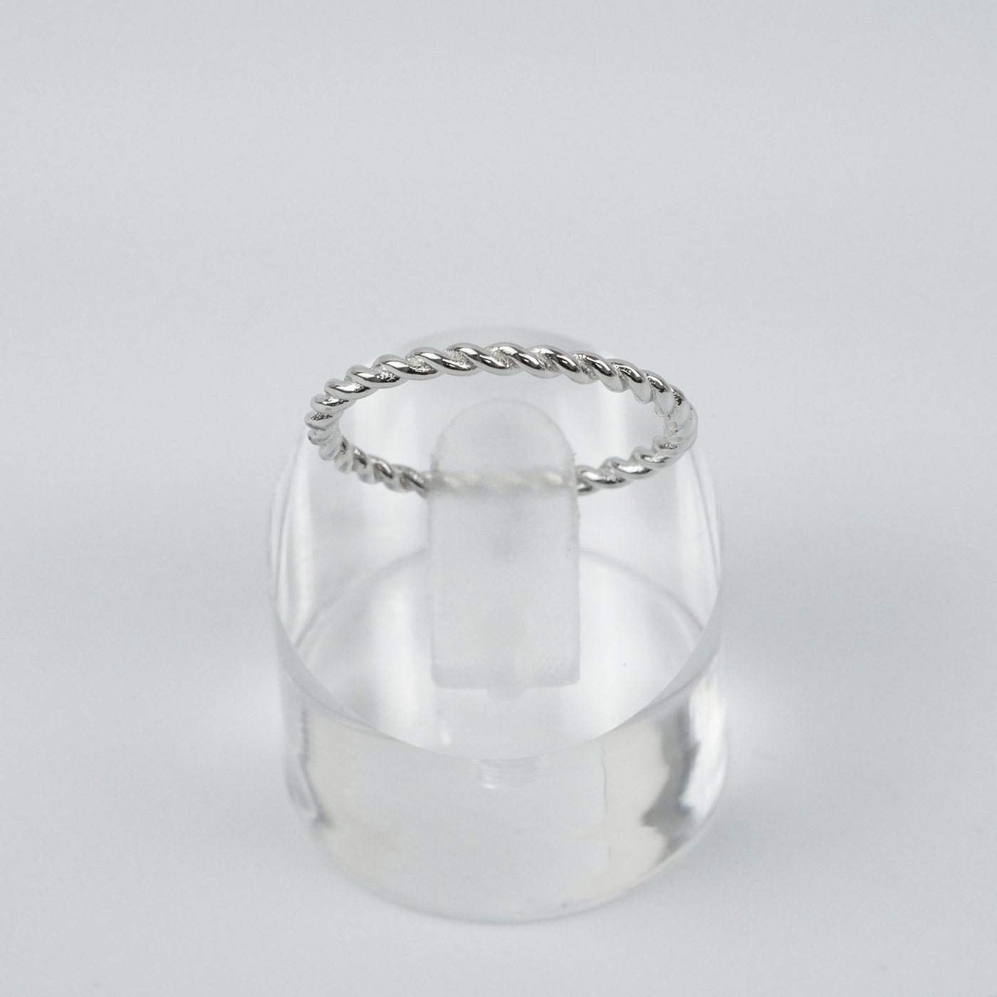 Silver ring with a twist design on a light grey background