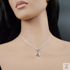 Mannequin wearing a silver necklace with a heart-shaped pendant against a dark background