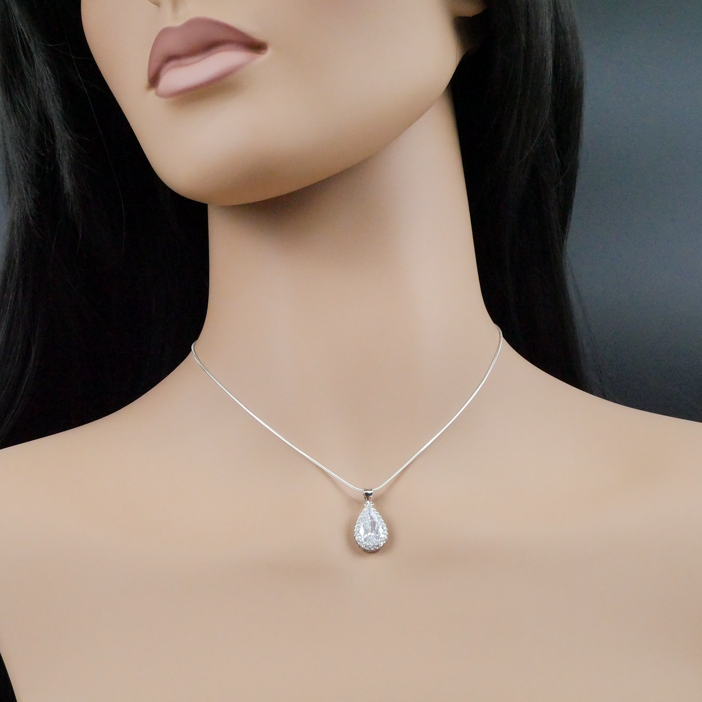 Mannequin wearing a silver teardrop necklace against a dark background