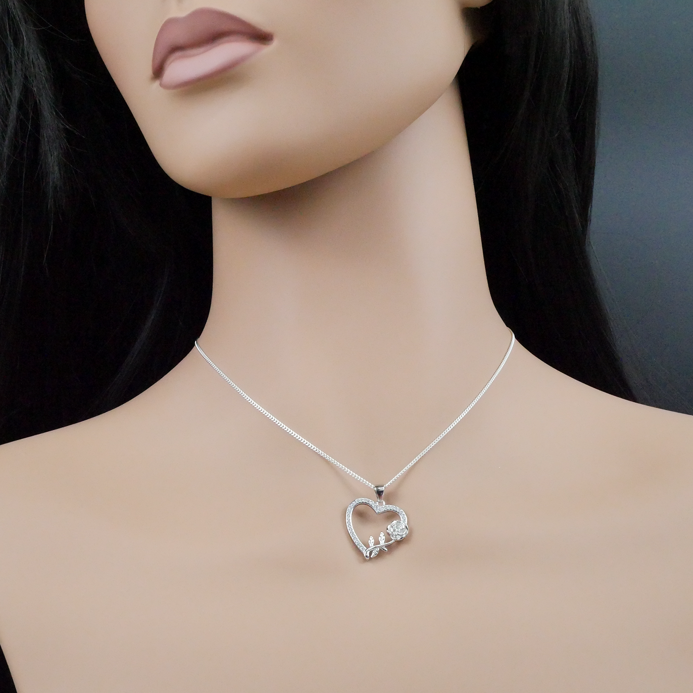 Silver necklace with a heart-shaped pendant on a mannequin
