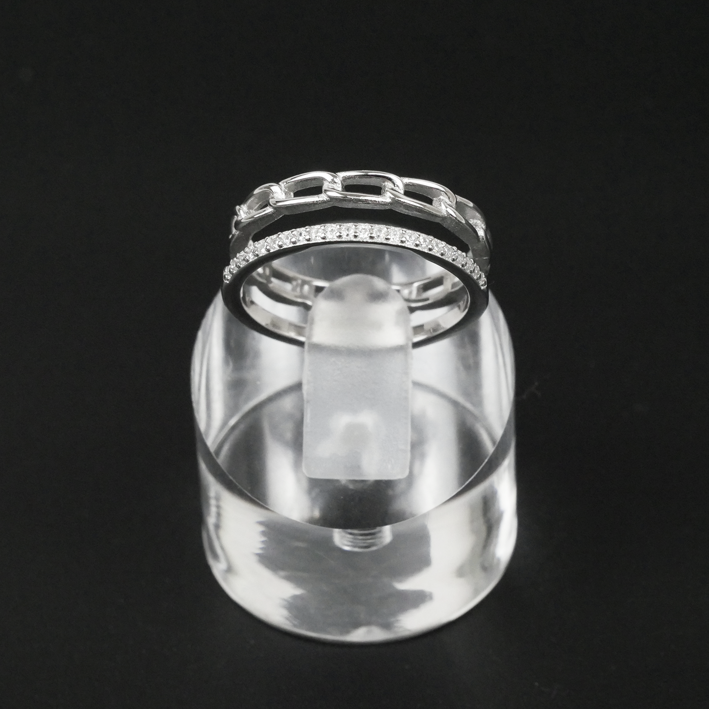 Silver ring with gemstones on a clear stand against a black background