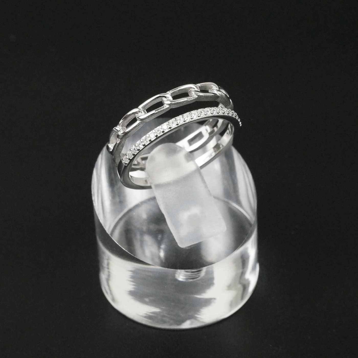 Silver ring with gemstones on a clear stand against a black background