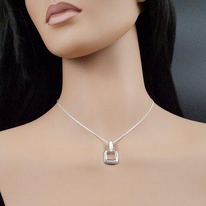 Silver necklace with a square pendant on a mannequin against a dark background