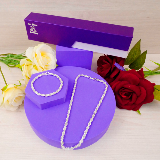 Silver necklace on a purple stand with a purple box and flowers in the background